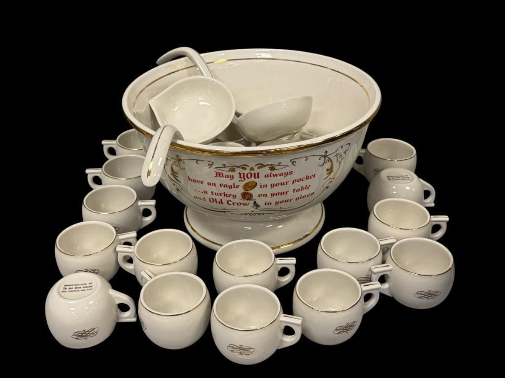 VINTAGE THE HALL CO. OLD CROW KENTUCKY WHISKEY PUNCHBOWL WITH CUPS AND LADDLES: FOOTED PUNCHBOWL WITH GILT AND RED LETTERING AND DESIGN, INCLUDES 20 CUPS AND TWO LADDLES 12" ROUND PUNCHBOWL