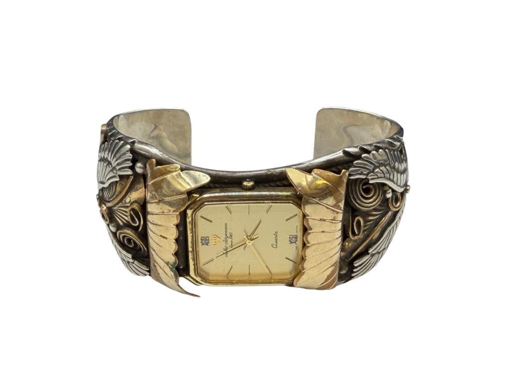 NAVAJO ALLEN CHEE ARTIST SIGNED STERLING SILVER TOOLED SILVER EAGLE, FEATHER, AND SCROLL WATCH CUFF: WITH JULES JURGENSEN WATCH, WATCH NEEDS BATTERY, QUARTZ WATCH, CUFF FEATURES EXCEPTIONAL DETAIL OF EAGLE ON BOTH SIDES OF CUFF, SIGNED BY ARTIST, BRASS ACCENTS 2 7/8" CUFF WRIST WIDTH, 1 1/2" THICK,