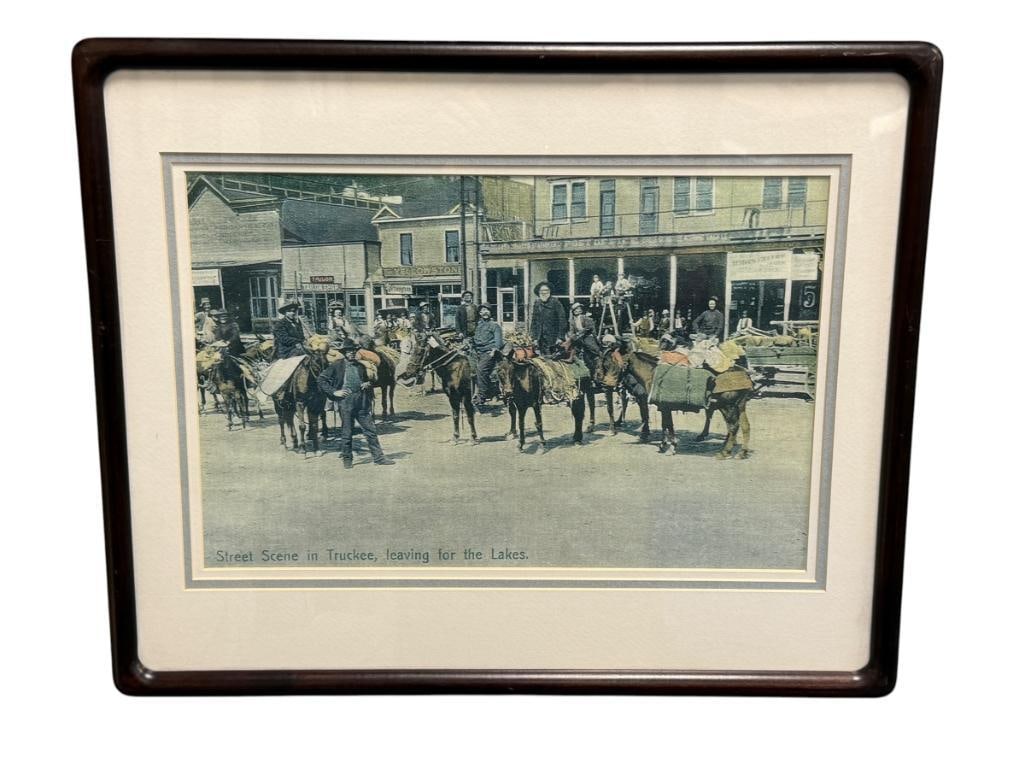 PRINT OF AN ANTIQUE PHOTOGRAPH STREET SCENE IN TRUCKEE, LEAVING FOR THE LAKES: ART DEPICTS MEN ON HORSEBACK ON A MAIN STREET, ORIGINALLY PRODUCED AS A POSTCARD PUBLISHED BY M. REIDER CIRCA 1909, FRAMED 21" X 17" FRAMED