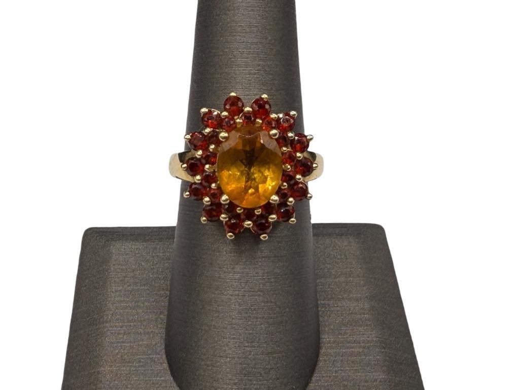 14K YELLOW GOLD OVAL CUT CITRINE AND ROUND CUT GARNET FASHION RING FEATURING FLOWER DESIGN: FLOWER DESIGN FEATURES AN OVAL CUT CITRINE ACCENTED BY 28 ROUND CUT GARNETS SIZE 7 1/4, 3/4" FRONT, 5.25 GRAMS, 10MM CITRINE, UP TO 2.5MM GARNETS