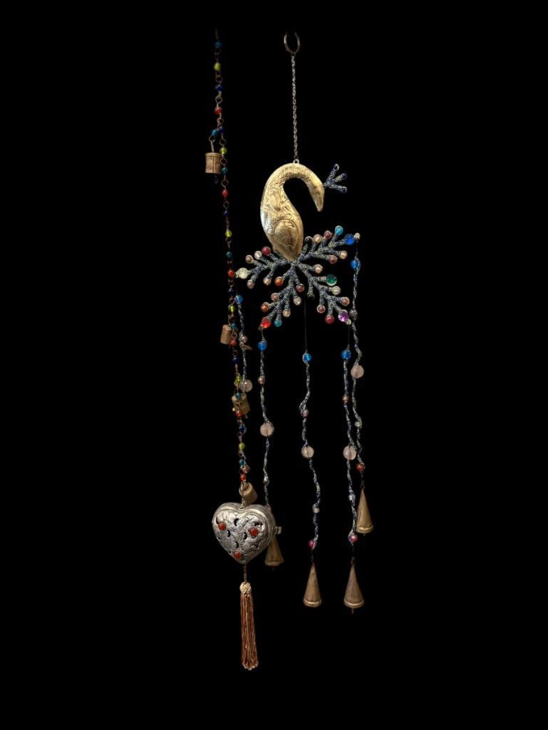 TWO BOHO-STYLE DECORATIVE BEADED WINDCHIMES WITH CONE AND CYLINDRICAL BELLS: EACH WIND CHIME IS DECORATED WITH BEADS AND BELLS, ONE FEATURES EXOTIC BIRD TOPPER, AND OTHER FEATURES AN ENGRAVED HEART 27" AND 32" H
