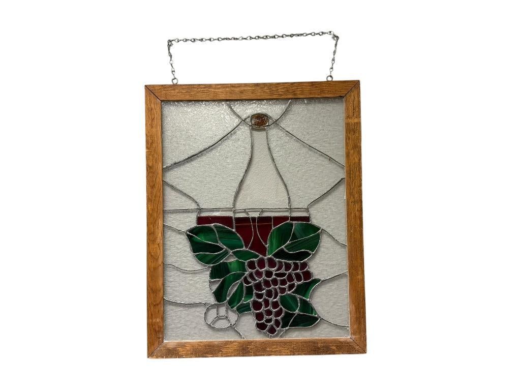 VINTAGE STAINED GLASS WINE BOTTLE GRAPE CLUSTER WINDOW PANEL IN WOOD FRAME: METAL CHAIN FOR HANGING ATTACHED AT TOP, WOOD FEATURES RUSTIC APPEAL, GREEN AND RED STAINED GLASS GRAPE DESIGN, APPEARS TO ONLY HAVE ON MINOR CRACK LESS THAN AN INCH 21" X 26" FRAME