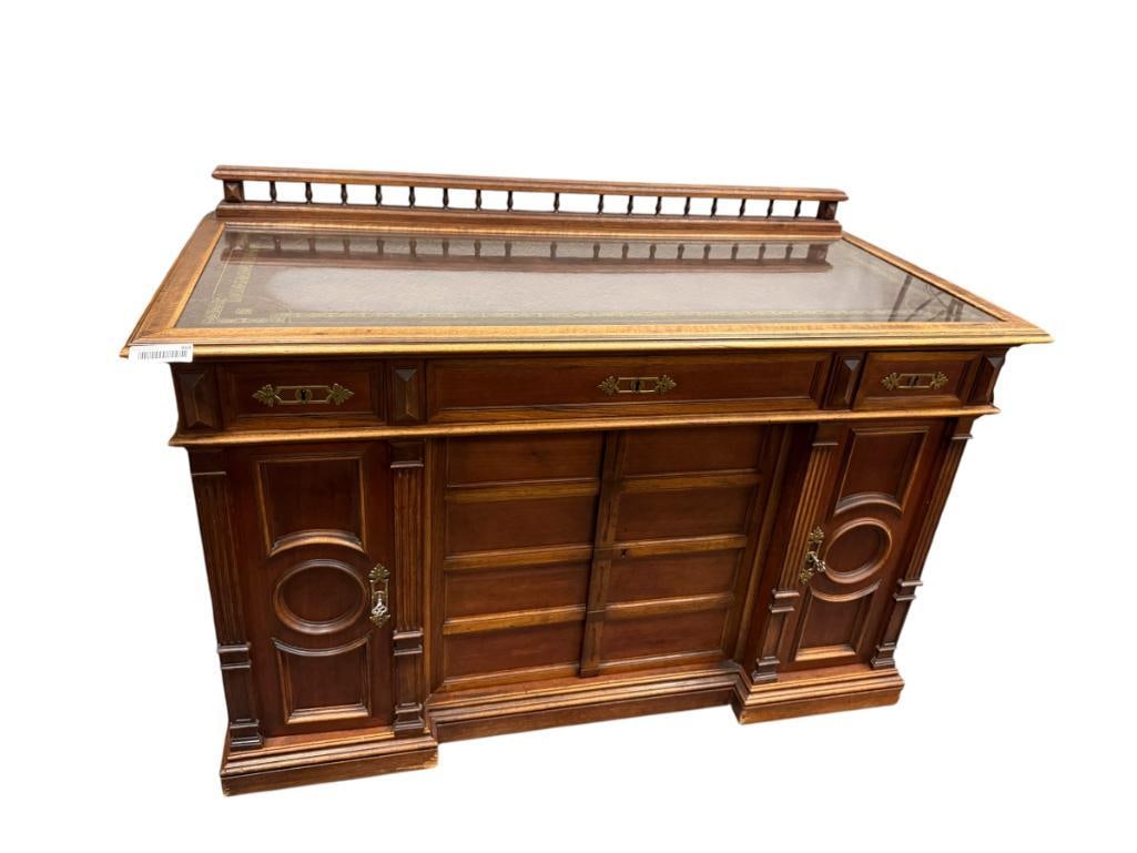 EARLY 20TH CENTURY MAHOGANY WRITING TABLE / DESK SOLID CONSTRUCTION WITH LEATHER TOP: GILT EDGE LEATHER TOP ENCASED WITH GLASS TOP, SMALL BACK GALLERY, FEATURES DOVETAIL CONSTRUCTED DRAWERS, DECORATIVE BRASS KEY HOLE HARDWARE, INCLUDES TWO KEYS WHICH ONLY WORK FOR TOP DRAWERS, SOME LIG