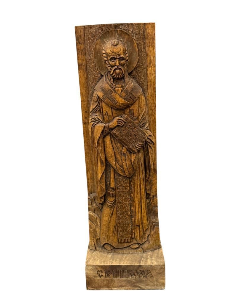 RELIGIOUS ICON HAND CARVED RELIEF FIGURAL PLAQUE OF SAINT NICHOLAS THE WONDERWORKER SIGNED: MADE FROM TWO PIECES OF WOOD, WITH CYRILLIC TEXT ON THE BASE, SIGNED ON THE BACK AND DATED 2000 21 1/2" H