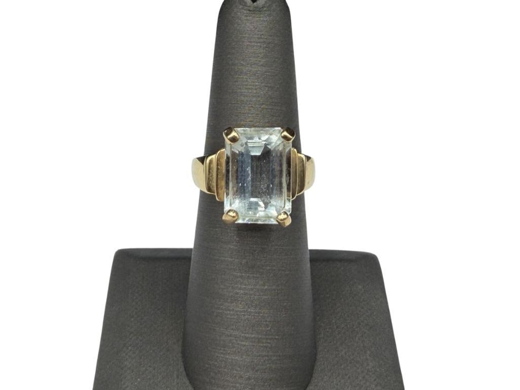 14K YELLOW GOLD EMERALD CUT 6.0CT AQUAMARINE RING: FEATURING AN EMERALD CUT AQUAMARINE PRONG SET WITH TAPERED DESIGN ON SHOULDERS OF SHANK SIZE 6 1/4, 5/8" FRONT, 5.49 GRAMS, APPROX. 6CT AQUAMARINE