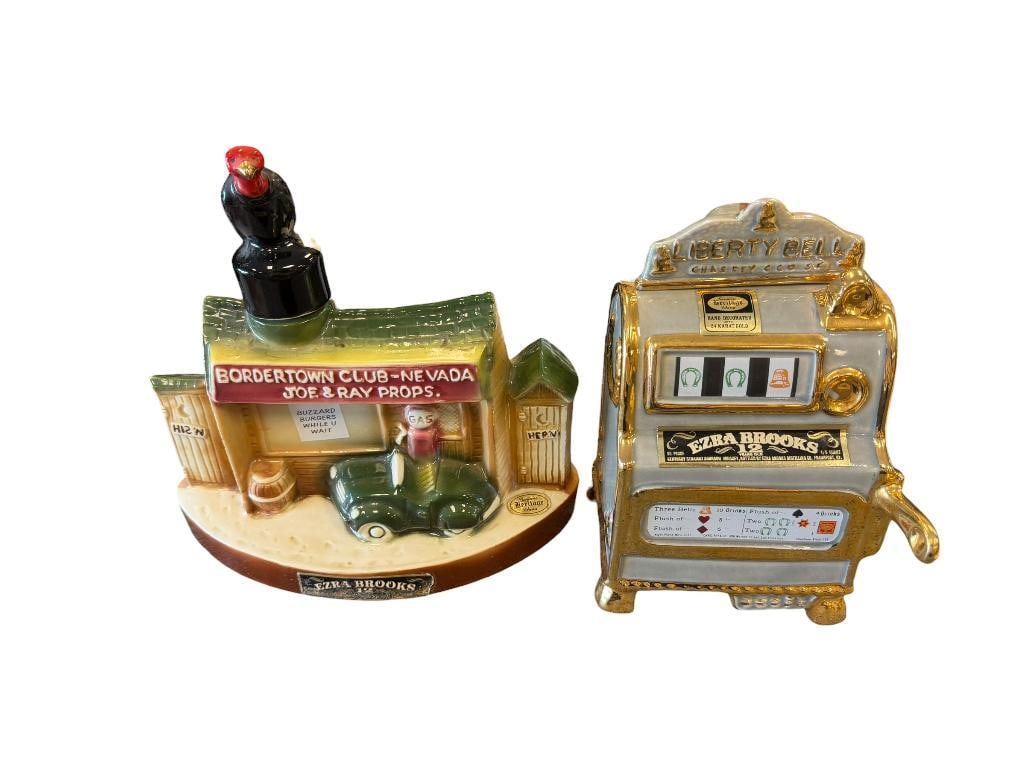 HERITAGE CHINA EZRA BROOKS LIBERTY BELLE AND BORDERTOWN JOE & RAY PROPS COLLECTIBLE DECANTERS: BORDERTOWN DECANTER DEPICTS GAS STATION SCENE WITH OUT HOUSES, VEHICLE AND GAS STATION, EMPTY, BROKEN CORK, AND LIBERTY BELLE SLOT MACHINE DECANTER WITH GILT ACCENTS, EMPTY, BOTH DECANTERS HAVE NO CRA