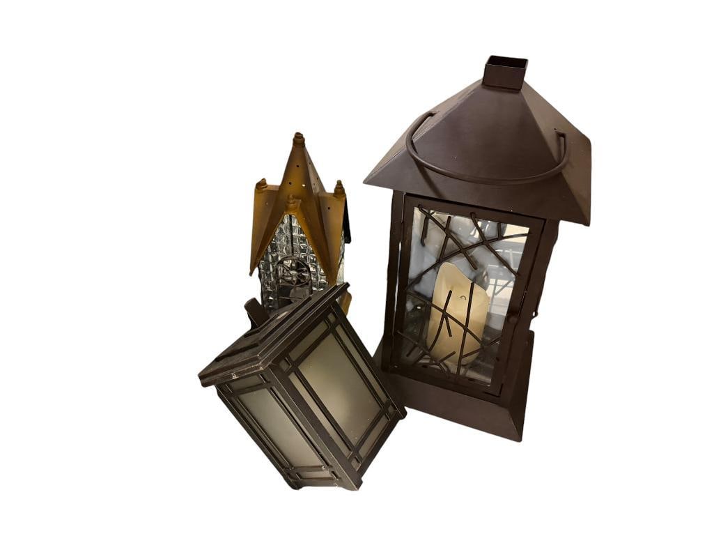 TWO METAL FIGURAL CANDLE LANTERNS AND ONE ELECTRIC OUTDOOR WALL LIGHT: OUTDOOR LIGHT MUST BE HARD WIRED, BOTH CANDLE LANTERNS FEATURE METAL AND GLASS DESIGN, GOOD CONDITION LARGEST IS 16" H