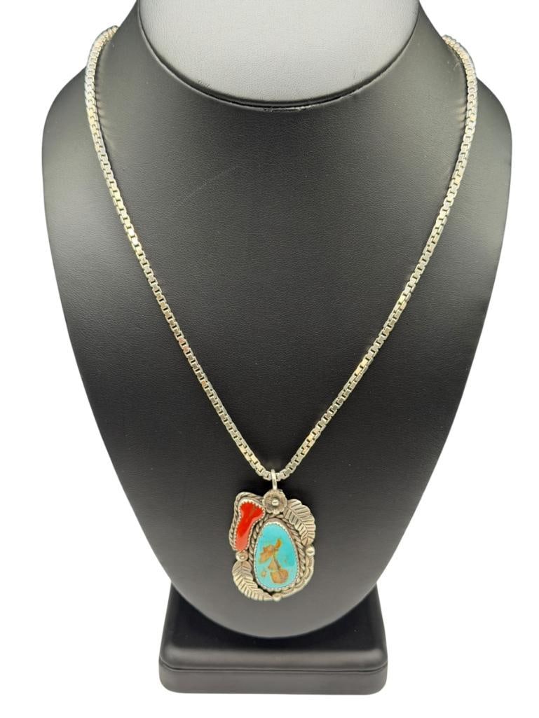 VINTAGE NAVAJO ARTIST SIGNED STERLING SILVER TURQUOISE AND CORAL PENDANT ON ITALIAN STERLING CHAIN: PENDANT FEATURES TURQUOISE, CORAL, AND FIGURAL TOOLED FEATHER ACCENTS, CHAIN IS STERLING SILVER BOX CHAIN MARKED "MILOR ITALY," PENDANT IS SIGNED BY ARTIST 26" X 1/8" NECKLACE, 2" PENDANT, 35.93 GRAMS