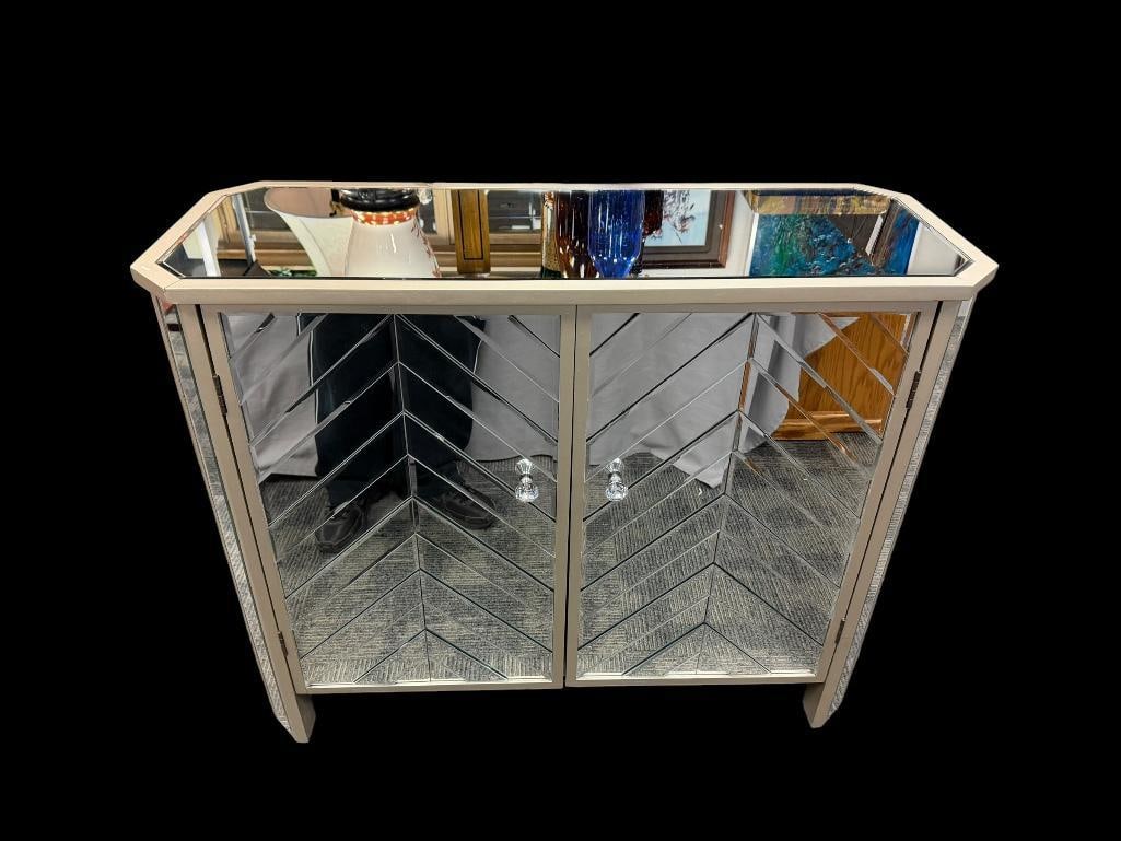 DECORATIVE MIRRORED ACCENT CABINET WITH MIRRORED PANELS AND BEWJELED KNOBS: CHEVRON STYLE DESIGN ON THE FRONT DOORS, NO CRACKED PANELS, SILVER TRIMMED 39" X 15" X 33"