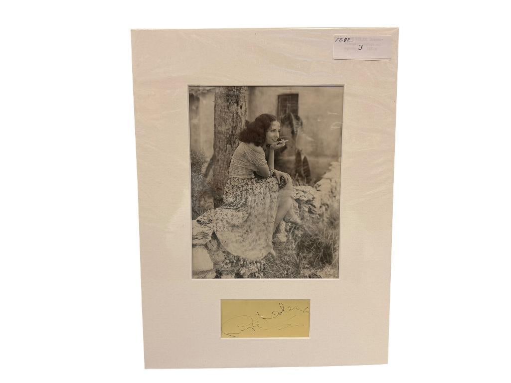 LUPE VELEZ 20TH CENTURY MEXICAN ACTRESS AUTOGRAPH AND BLACK AND WHITE PHOTOGRAPH: LUPE VELEZ (1908-1944) WAS A MEXICAN ACTRESS DURING THE GOLDEN AGE OF HOLLYWOOD, HAD HER FIRST APPEARANCE IN THE UNITED STATES IN 1927, PHOTO DEPICTS LUPE SITTING NEAR A TREE SMOKING A CIGARETTE,
