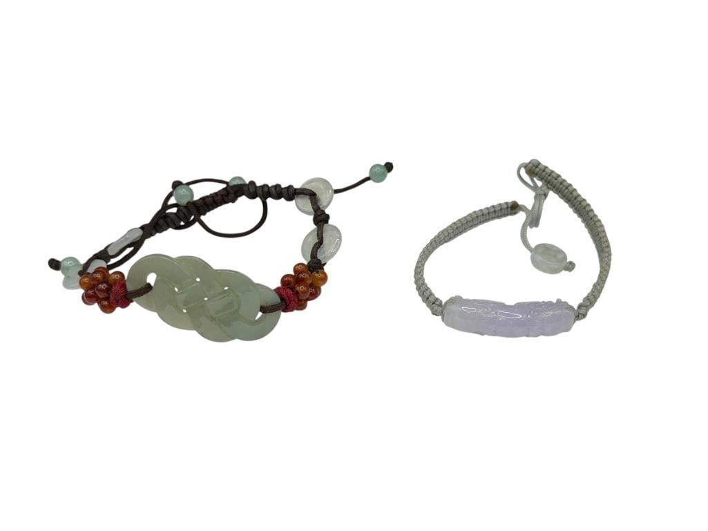 TWO CARVED JADE BRACELETS INCLUDING CARVED GREEN JADE AND LAVENDER JADE DRAGON: BOTH FEATURE WOVEN THREAD BANDS WITH ADJUSTABLE LENGTH GREEN JADE PIECE IS 1 1/2" AND LAVENDER JADE PIECE IS 1 1/4"