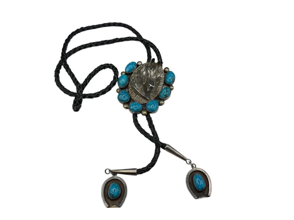 VINTAGE NAVAJO MARK CHEE ARTIST SIGNED STERLING SILVER TURQUOISE HORSE BOLO TIE: FEATURING HORSE BUST IN RELIEF ACCENTED BY OVAL SHAPED TURQUOISE SET IN HORSESHOE DESIGN, BLACK LEATHER BOLO TIE, SIGNED BY ARTIST "M. CHEE" 2 5/8" BOLO CLIP, CLIP WEIGHS APPROX. 125 GRAMS