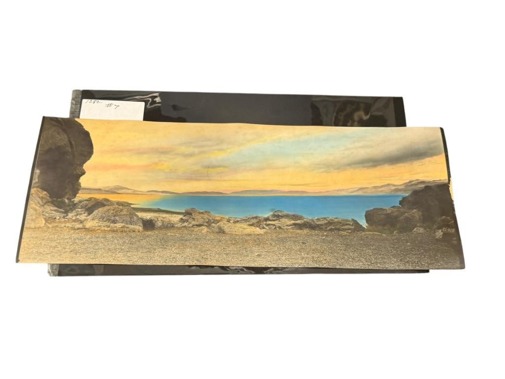 1930'S HAND COLORED PHOTOGRAPH OF PYRAMID LAKE LANDSCAPE BY NEVADA PHOTO SERVICE: TRANQUIL LANDSCAPE OF PYRAMID LAKE WITH COLORED WATER AND SKY, STAMPED ON THE BACK, DAMAGE ON THE RIGHT EDGE 17" X 6 1/2"