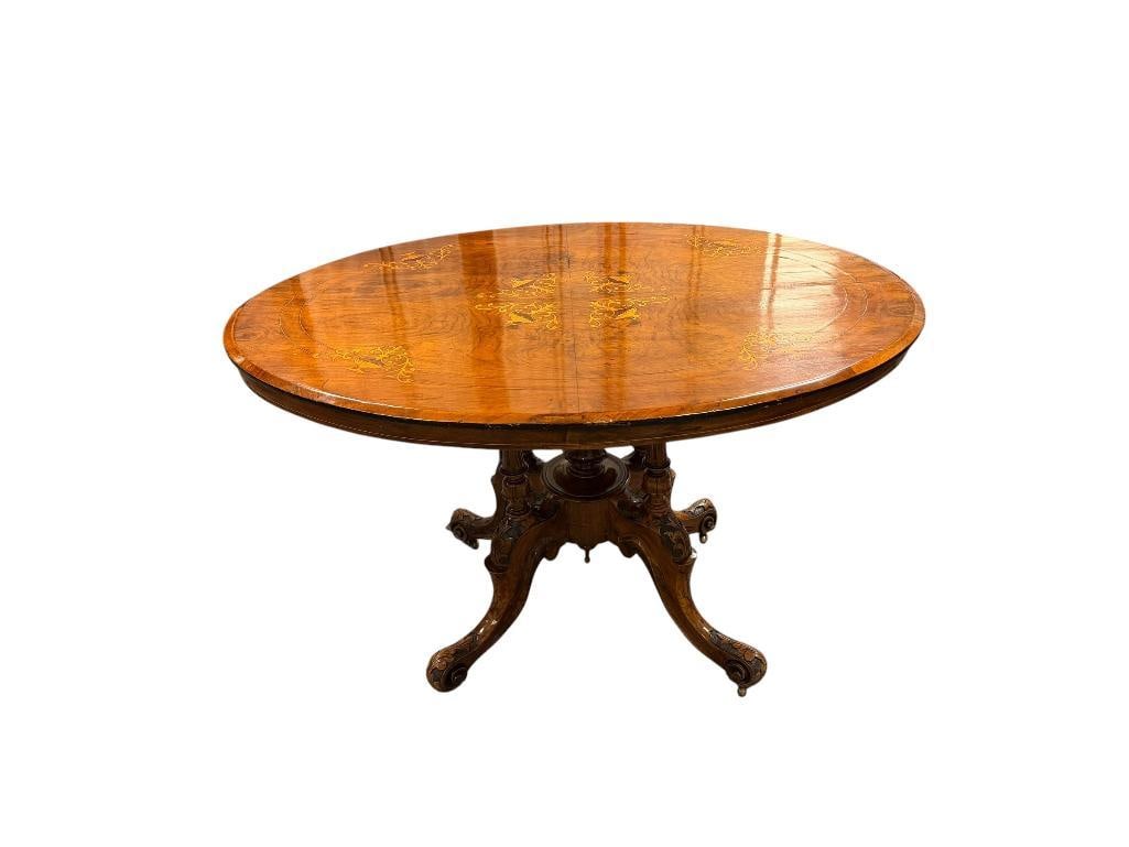 ANTIQUE VICTORIAN ERA BURR WALNUT OVAL LOO TABLE WITH INTRICATE FLORAL INLAY MARQUETRY: CARVED FOUR FOOTED PEDESTAL WITH CARVED COLUMNS AND LEAF DESIGN, BRASS LOCKING MECHANISM, IN GOOD CONDITION FOR ITS AGE WITH NO HEAVY WEAR OR REPAIRS 46" X 33" X 28"