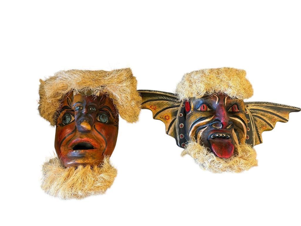 VINTAGE HAND CRAFTED WOODEN DEMON MASKS FROM MEXICIO POSSIBLY SONORA PASCOLA MASKS YAQUI OR MAYO: HAND CARVED AND PAINTED WOODEN MEXICO FOLK ART DANCE MASKS, DEMON MASK WITH WINGS AND HUMAN MASK WITH CENTRAL DEMON FIGURE, BOTH WITH COARSE FIBER ON TOP OF THE HEAD AND ON THE CHIN 12" AND 19" L