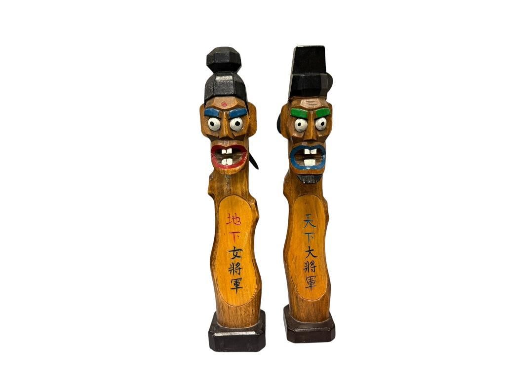 VINTAGE HAND CARVED KOREAN JANGSEUNG GUARDIAN FIGURES: TRADITIONAL VILLAGE TOTEM FIGURES WITH WIDE EYES AND PROMINENT TEETH, CARVED SCRIPTURES READ FEMALE GENERAL AND GREAT GENERAL UNDER HEAVEN, USED TO FRIGHTEN AWAY EVIL SPIRITS AND BRING GOOD FORTUNE