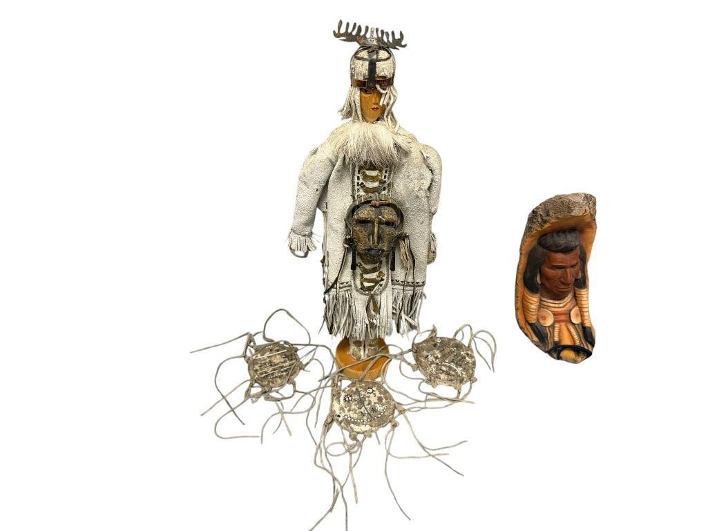 HAND CRAFTED INDIGENOUS - INSPIRED DOLL WITH BUCKSKIN CLOTHING, CARVED WOODEN FACE, FRINGED DETAIL: FEATURES FUR ACCENT AND METAL ADORNMENTS, MOUNTED ON WOODEN BASE, INCLUDES THREE BUCKSKIN DRUMS WITH PETROGLYPHS AND FRINGED / KNOTTED EDGES 13" DOLL 