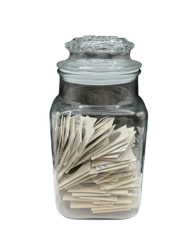 LIDDED GLASS JAR FILLED WITH MORE THAN 100 FOREIGNS COINS FROM ALL OVER THE WORLD: ALL IN COIN FLIPS JAR IS 9" H
