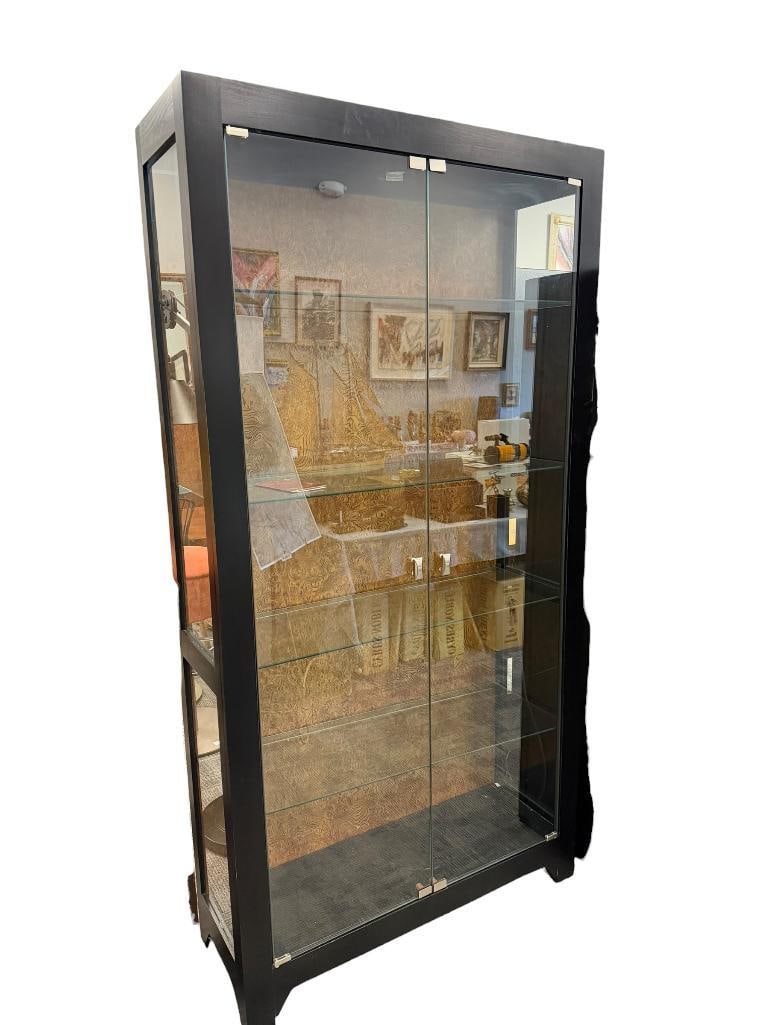 HOWARD MILLER ILLUMINATING DISPLAY CABINET WITH GLASS FRONT DOORS AND WOOD GRAIN BACK MODEL. 680-...: BLACK FINISH CABINET, FEATURES CLEAR GLASS SIDE PANELS AND FOUR ADJUSTABLE GLASS SHELVES WITH PLATE GROOVE, TESTED + 40" X 14" X 78"