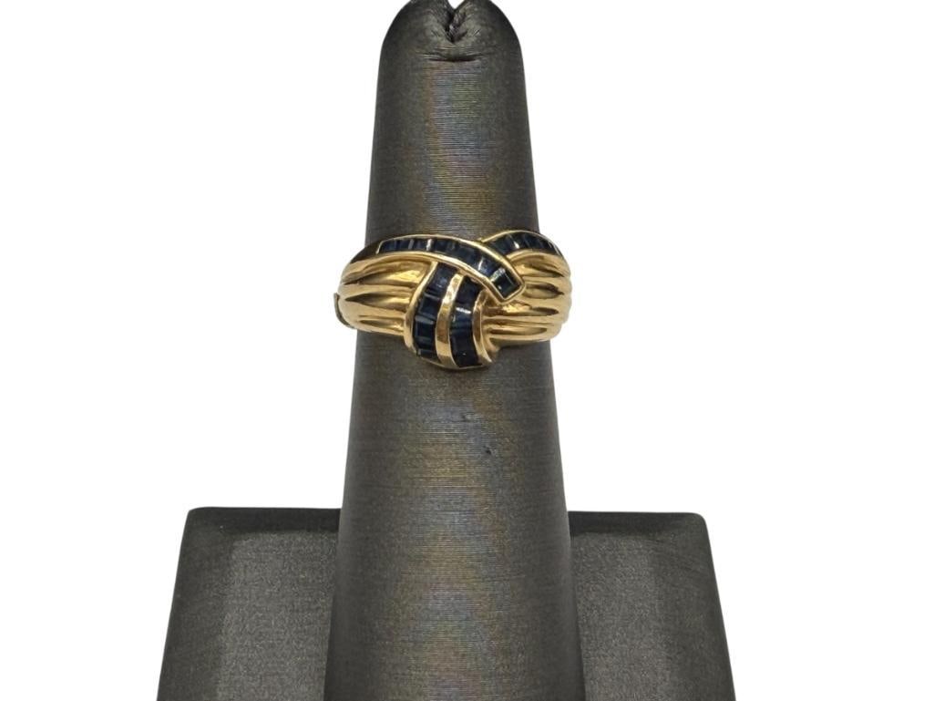 14K YELLOW GOLD CHANNEL SET BAGUETTE CUT SAPPHIRE BYPASS DESIGN RING: FEATURING RIBBED DESIGN AND 20 BLUE SAPPHIRES, MOUNTED WITH BANDS TO MODIFY SIZE SIZE 5 1/4, 1/2" FRONT, UP TO 2MM X 2MM SAPPHIRES, 3.71 GRAMS