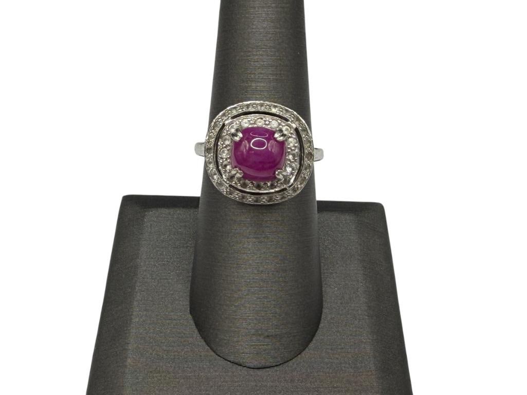 STERLING SILVER CABOCHON RUBY AND WHITE TOPAZ FASHION RING: FEATURING A CABOCHON RUBY IN CENTER ACCENTED BY HALOS OF WHITE TOPAZ, MARKED "THAILAND" SIZE 7 1/4, 5/8" FRONT, 8MM X 8MM RUBY, 1MM WHITE TOPAZ, 4.17 GRAMS