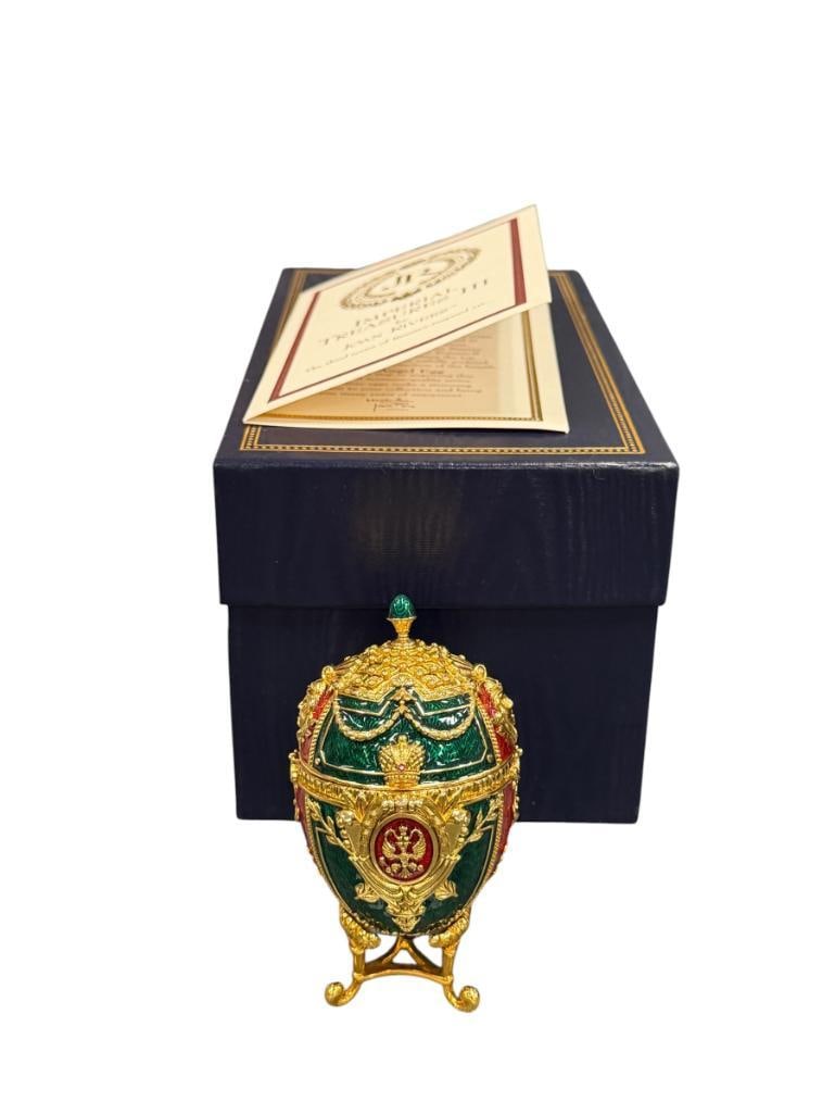 JOAN RIVERS IMPERIAL TREASURES III THE ANGEL EGG FABERGE INSPIRED IMPERIAL EASTER EGG WITH CHARM: RED AND GREEN ENAMELED EGG WITH GOLD FINISH, INCLUDES STAND WITH CHARM, CERTIFICATE AND ORIGINAL BOX IN NEAR MINT CONDITION 3 1/2" H