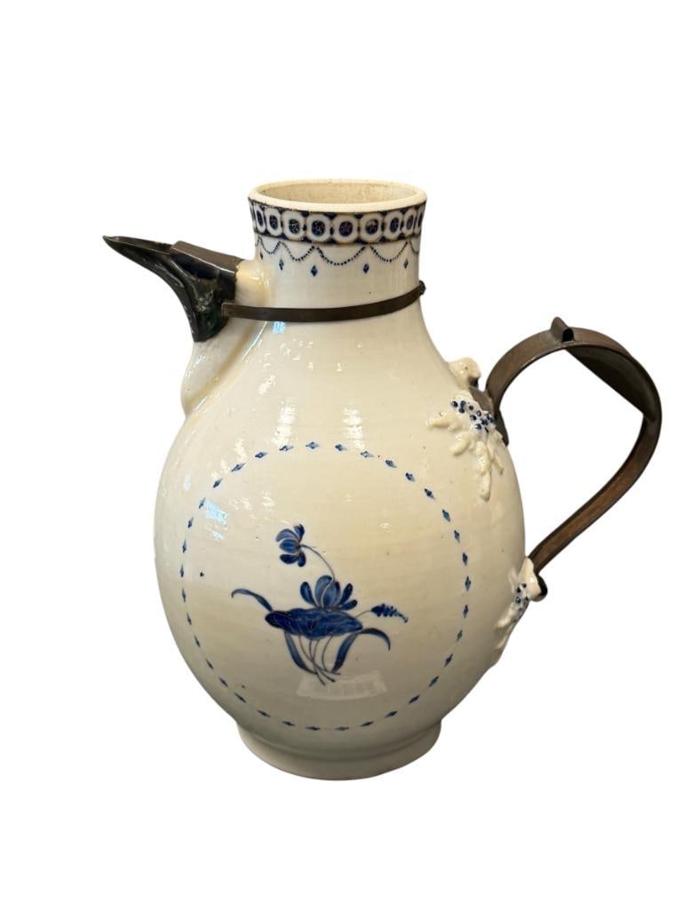 ANTIQUE MAKE DO FAIENCE PITCHER CIRCA LATE 19TH CENTURY: HAND PAINTED BLUE FLORAL DESIGN WITH GILT ACCENTS, BULBOUS BODY WITH METAL OVERLAY DECORATIVE SPOUT, HANDLE HAS BEEN REPLACED / REPAIRED WITH A METAL HANDLE, MISSING TOP 7 3/4" H