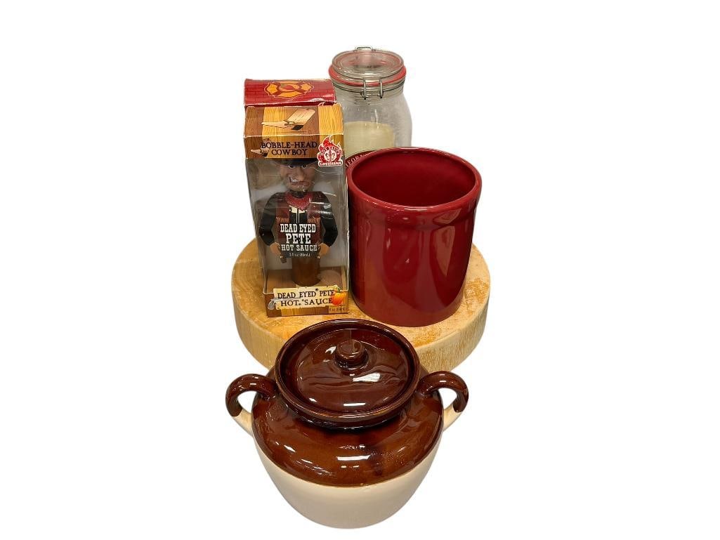 KITCHEN ITEMS MCCOY POTTERY BEAN POT, THICK ROUND CUTTING BOARD, USA POTTERY UTENSIL HOLDER: SUNKIST CALIFORNIA PISTACHIOS JAR AND TWO SEALED BOTTLES OF BOBBLE HEAD HOT SAUCE