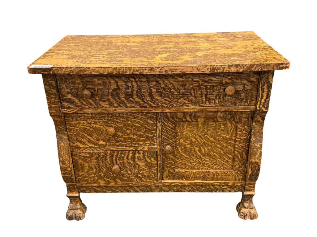 EARLY 1900'S PAINTED GRAIN TIGER OAK WASHSTAND WITH CARVED FEET: FEATURES THREE DRAWERS WITH SINGLE DOOR BOTTOM CABINET, PAINTED GRAIN, FINISH SHOWS HEAVY WEAR ON TOP 32" X 28" X 26"