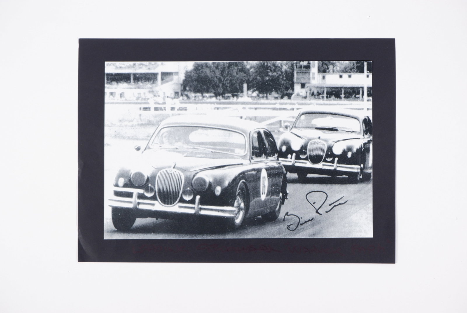 PITT: A black and white image of 1961 ATCC Winner, Bill Pitt, in a Jaguar Mark 1 3.4. Pitt signature: PITT: A black and white image of 1961 ATCC Winner, Bill Pitt, in a Jaguar Mark 1 3.4, image signed by Pitt in black marker; image on paper, with black backing, measures 29.5cm wide, 21cm high overall.