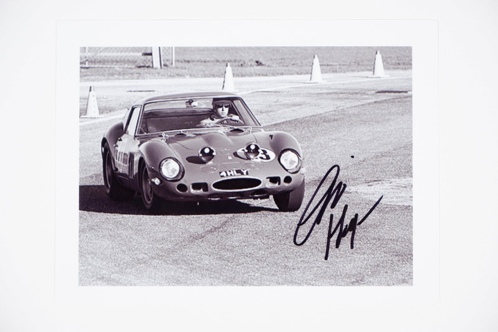 FERRARI/HAYES: Picture of Charlie Hayes racing a Ferrari 250 GTO at Daytona, 1965. Hayes signature: FERRARI/HAYES: A black and white picture of Charlie Hayes racing a Ferrari 250 GTO at Daytona, 1965, image signed by Hayes in black; on photographic paper, image measures 21cm wide, 15.5cm high overal