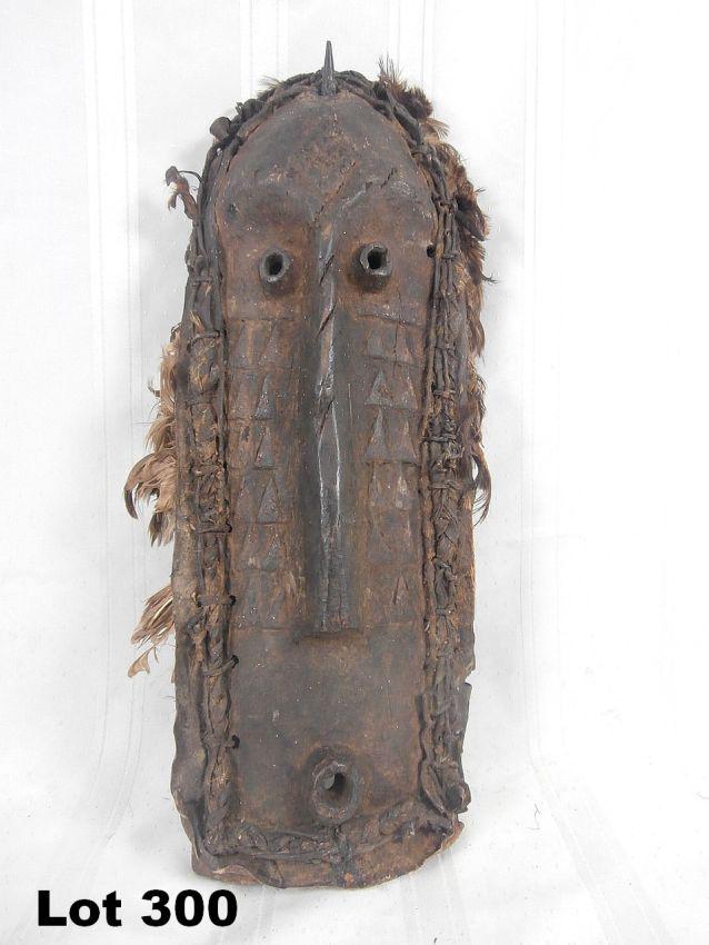 Carved Wood Mask with Leather & Feathers: Carved wood mask with leather & feathers decorations. 18" tall.