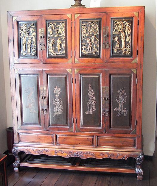 18th C Chinese temple chest: 18th C Chinese temple chest incorporating upper and lower compartments containing shelves and drawers. Upper cupboard doors are carved and gilded scenes. The lower doors are incised floral decorations