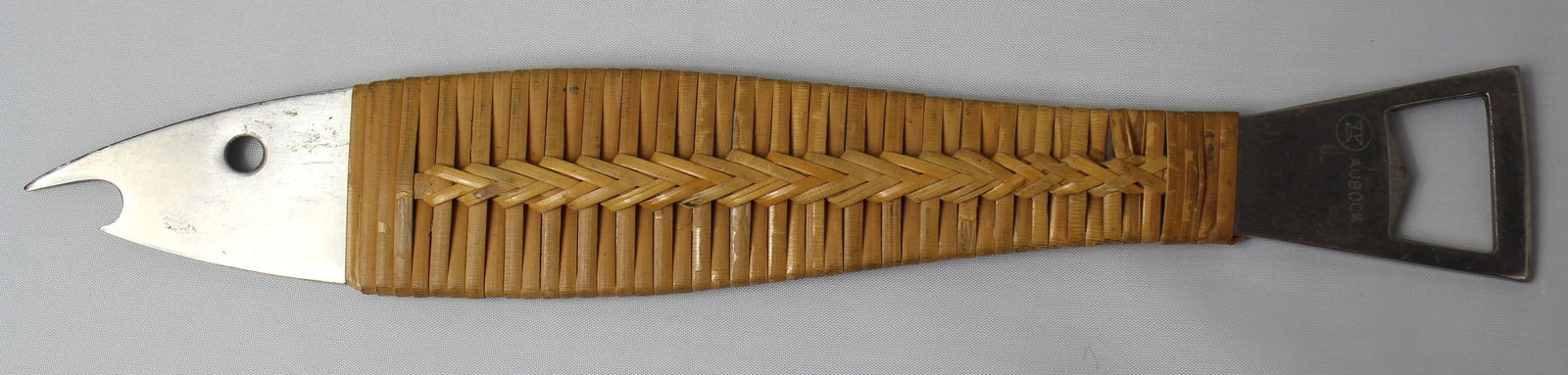 Carl Aubock Neptune Fish Bottle Opener: Carl Aubock Neptune Fish Bottle Opener. A nice mid-century fish shaped bottle opener with rattan wrap. Both the mouth and tail are openers. It is signed "Aubock" on the tail with a logo of an anvil an