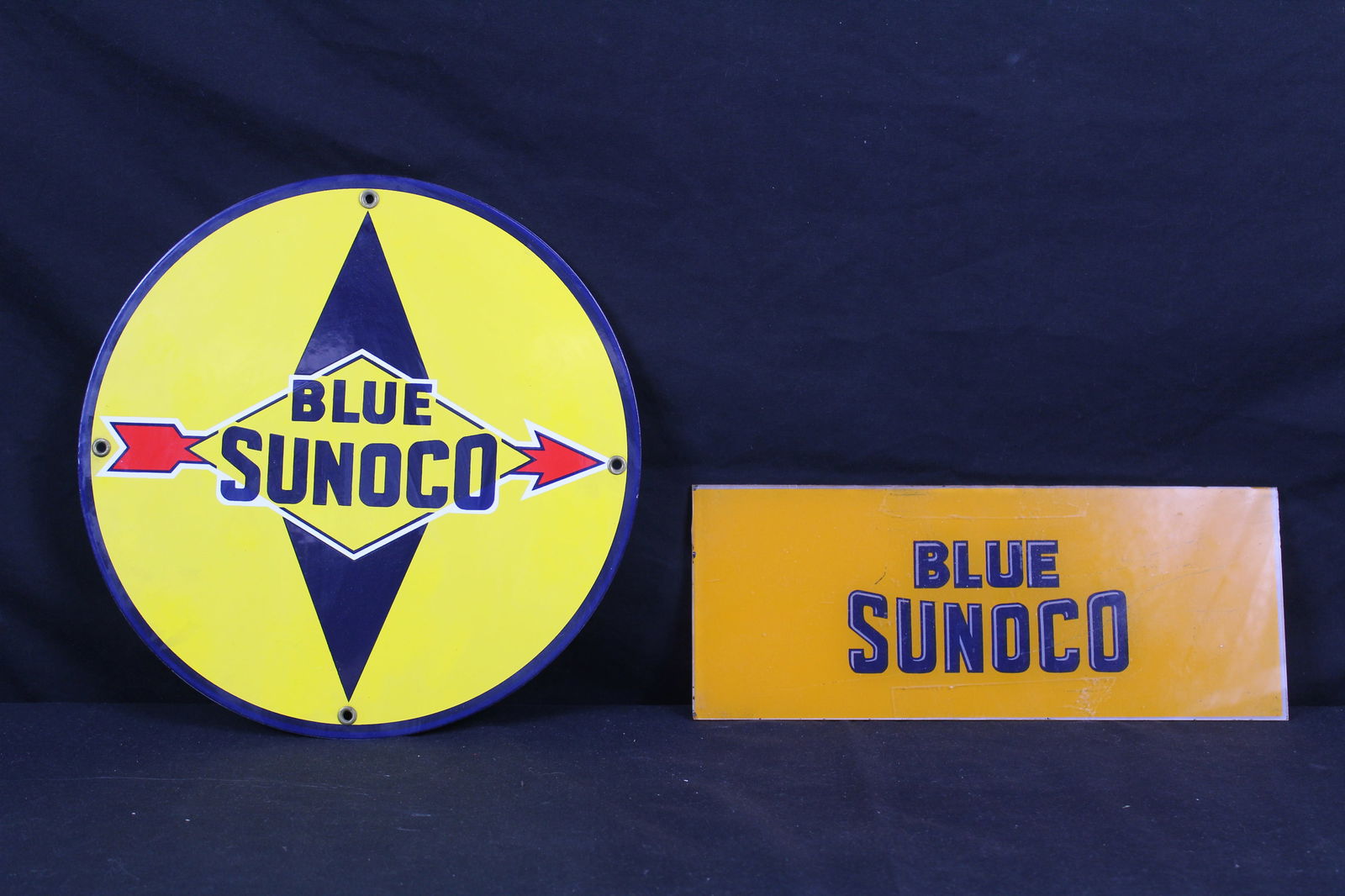 Two Blue Sunoco Glass and Porcelain Signs: Two Blue Sunoco Glass and Porcelain Signs. The first Blue Sunoco sign is the orange glass one that says "Blue Sunoco" in blue lettering that appears to be from a light. The second sign is a porcelain