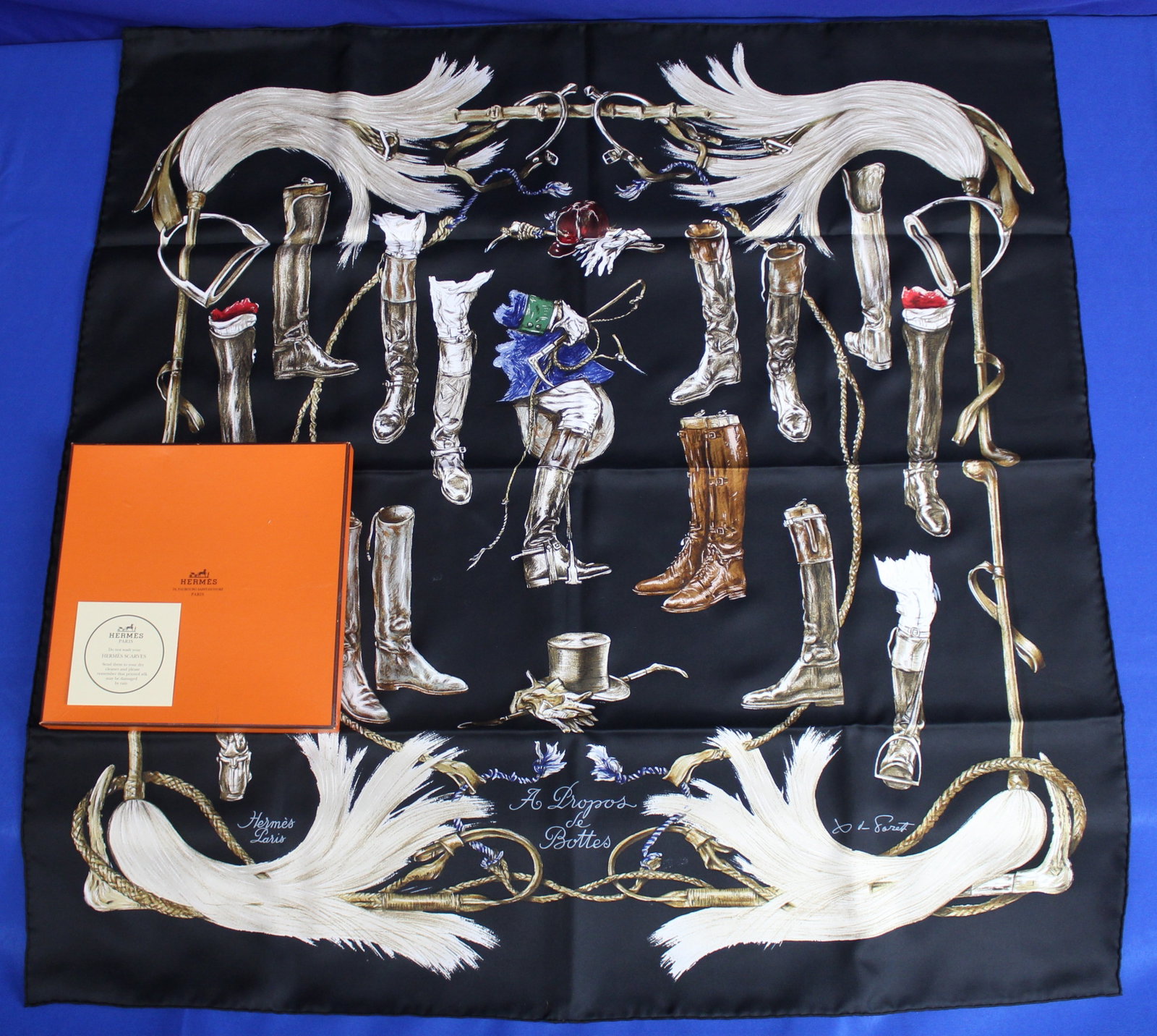 Hermes "A Propos De Battles" Silk Scarf: Hermes "A Propos De Battles" 90cm silk scarf with boots, top hats, and a jockey. The scarf has the title on the bottom middle and on the bottom left is a Hermes signature along with the signature of t