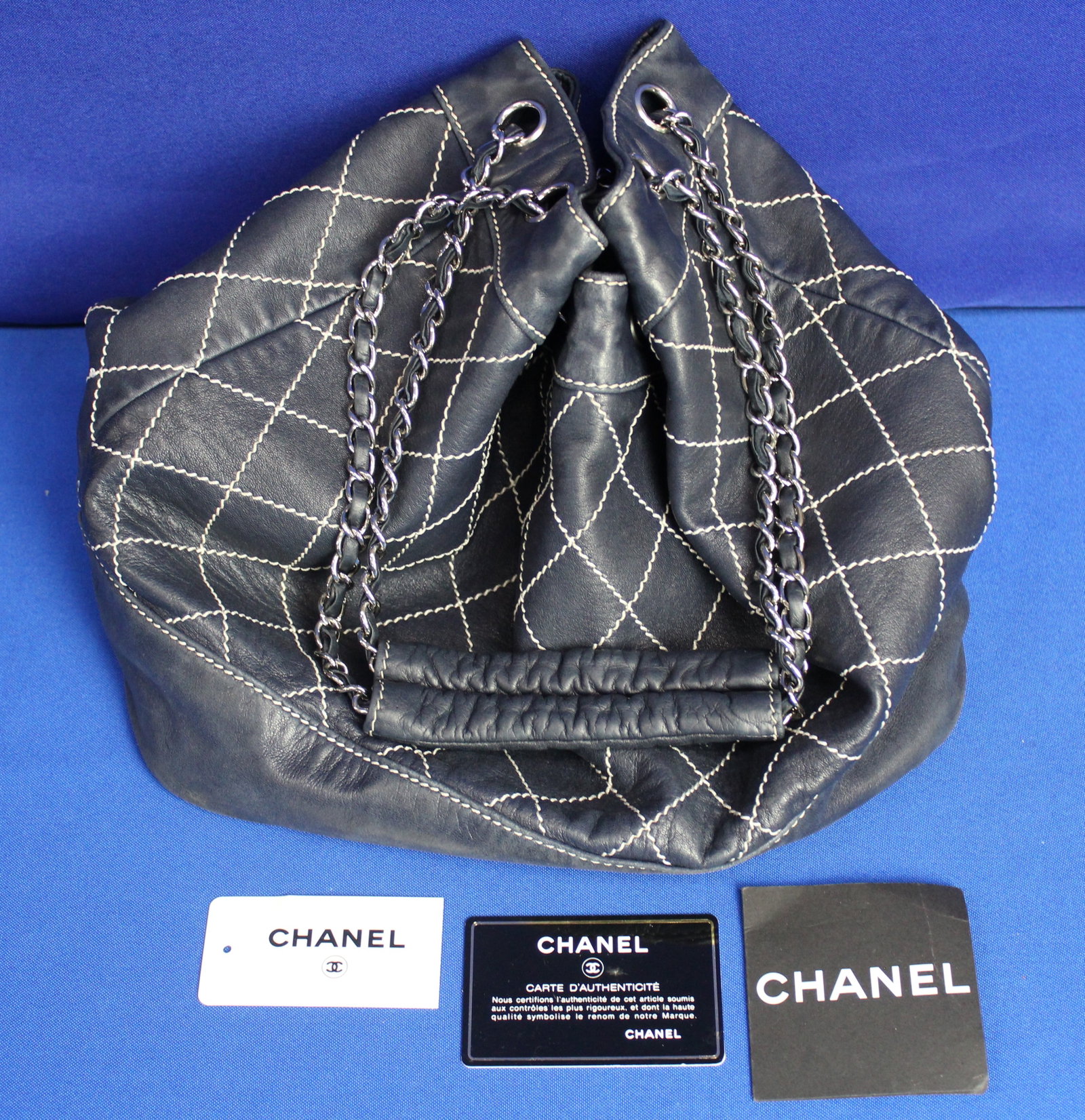 Chanel Dark Blue Bag: Authentic dark blue Chanel bag with the authenticity card and the original tags. Inside the bag is the Chanel Label. The bag is dark blue with a white pattern. Overall the bag is in excellent conditio