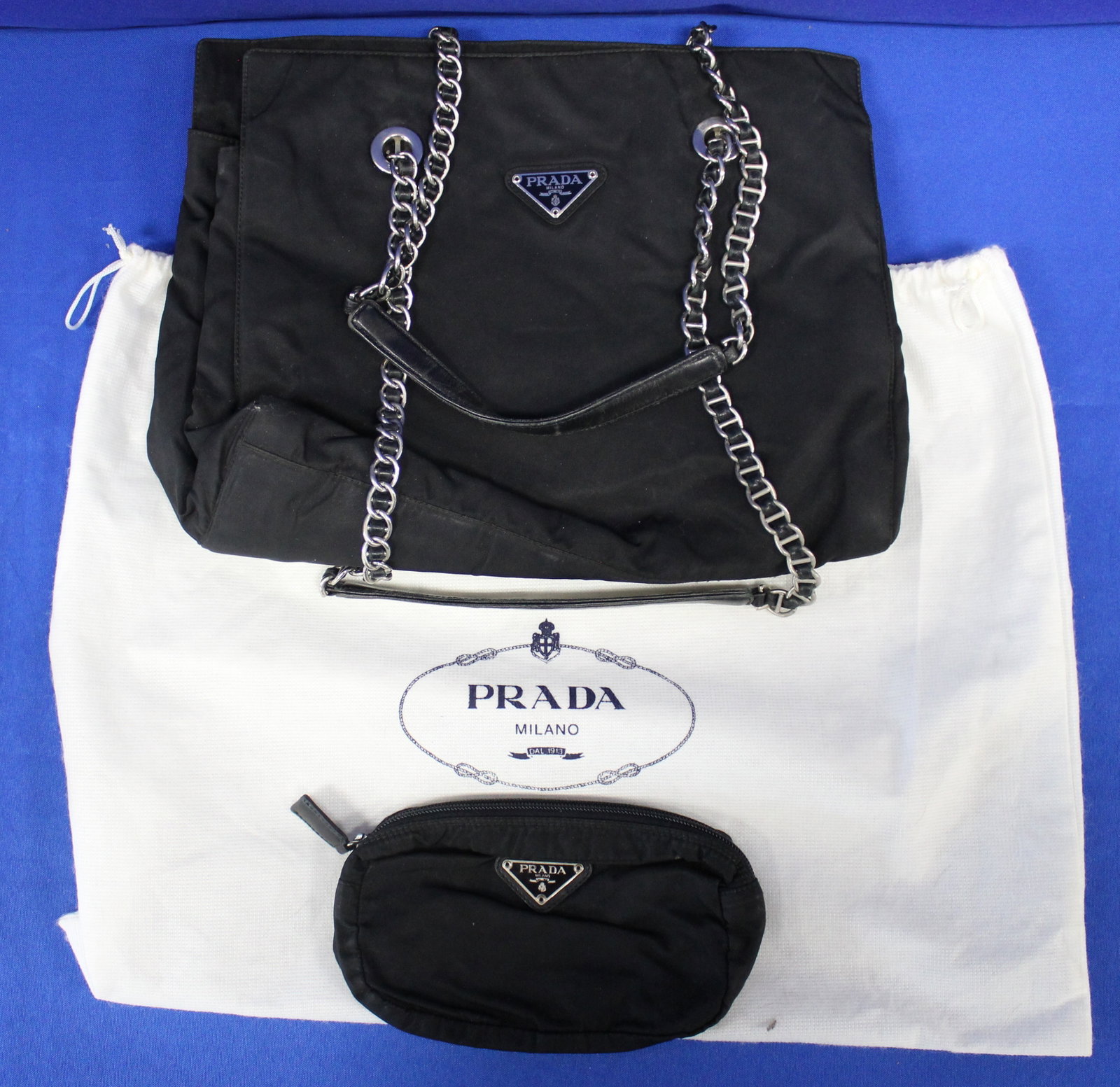 Prada Nylon Bag with Nylon Cosmetic Pouch: Authentic black Prada bag with cosmetic pouch with white Prada protective bag. Both the bag and pouch have the metal Prada badge outside and the Prada label inside. The bags have some light wear, but 