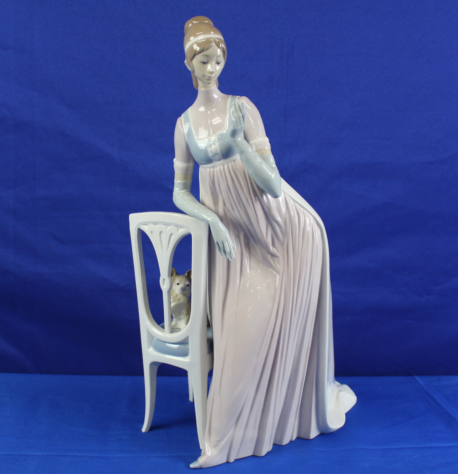 Lladro "Lady Empire" Figurine: Large "Lady Empire" Lladro figurine of a lady in a pink dress leaning against a chair with a dog on the chair. The bottom of the figurine is labeled Lladro and overall is in excellent condition. The f