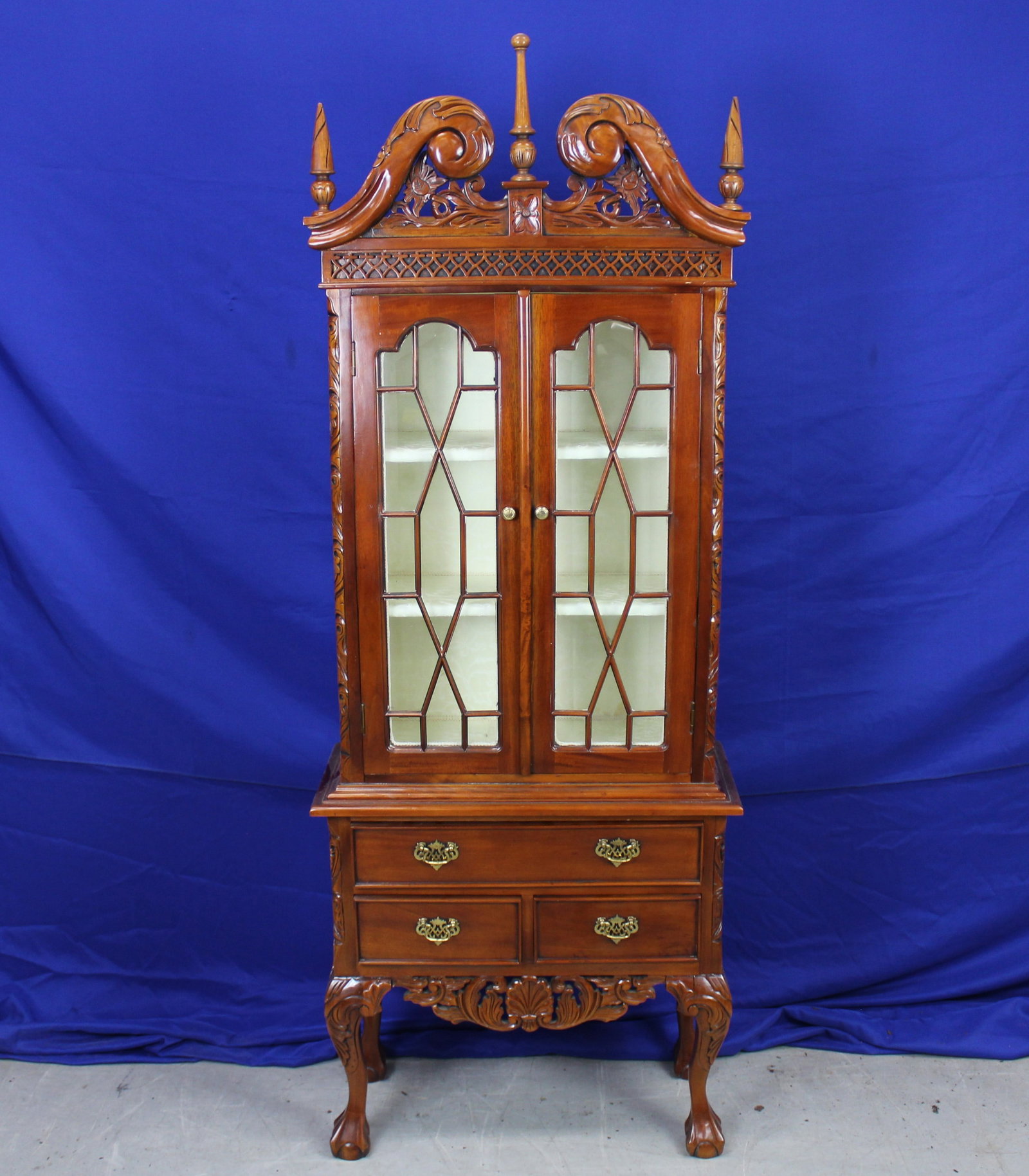 Chippendale Style 2 Piece China Cabinet: Two piece Chippendale style china cabinet with ornate carving. The top has glass doors with two shelves and the bottom has three drawers. Two finials are slightly loose along with some very light