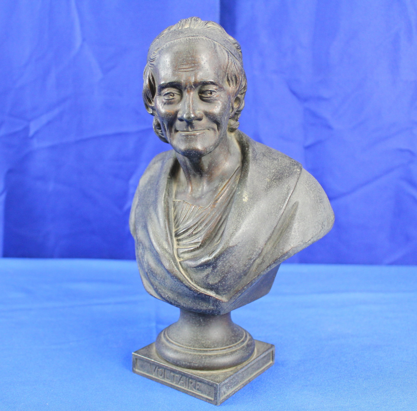 Voltaire Small Bronze Bust: Small bronze bust of philosopher and writer Voltaire whose name is on the front of the base. The bust has some light patina but overall is in excellent condition. Wear is consistent with age and use.