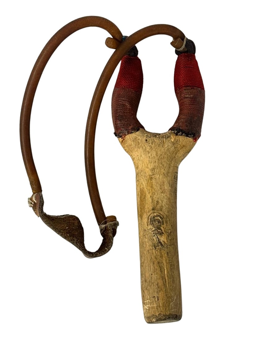 Vintage Wooden Slingshot with Leather Pouch and Red Wrap 9x3x1 in: This vintage wooden slingshot is a classic example of rustic craftsmanship. It features a solid wooden handle with a natural finish, giving it an authentic and traditional look. The handles are wrappe