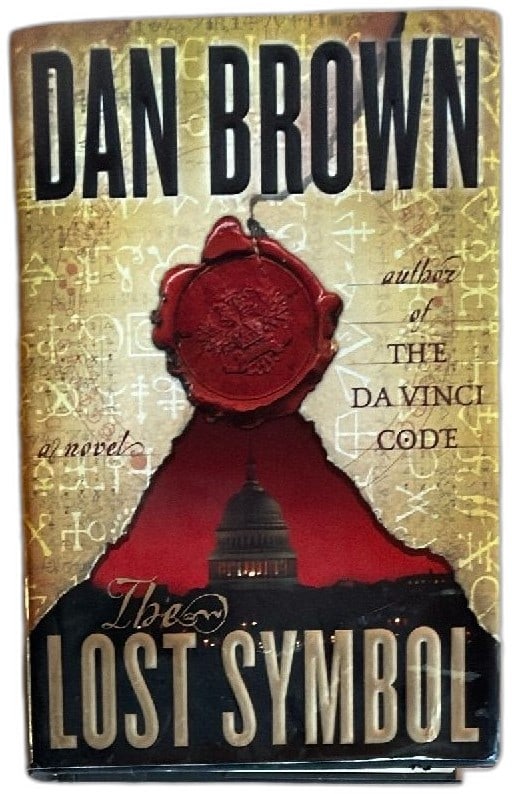 Dan Brown The Lost Symbol First Edition Hardcover Doubleday 2009 Thriller Novel: Dan Brown The Lost Symbol first edition hardcover book, published by Doubleday in 2009. Features signature gold-and-red dust jacket with wax seal design and bold typography. Bestselling thriller from