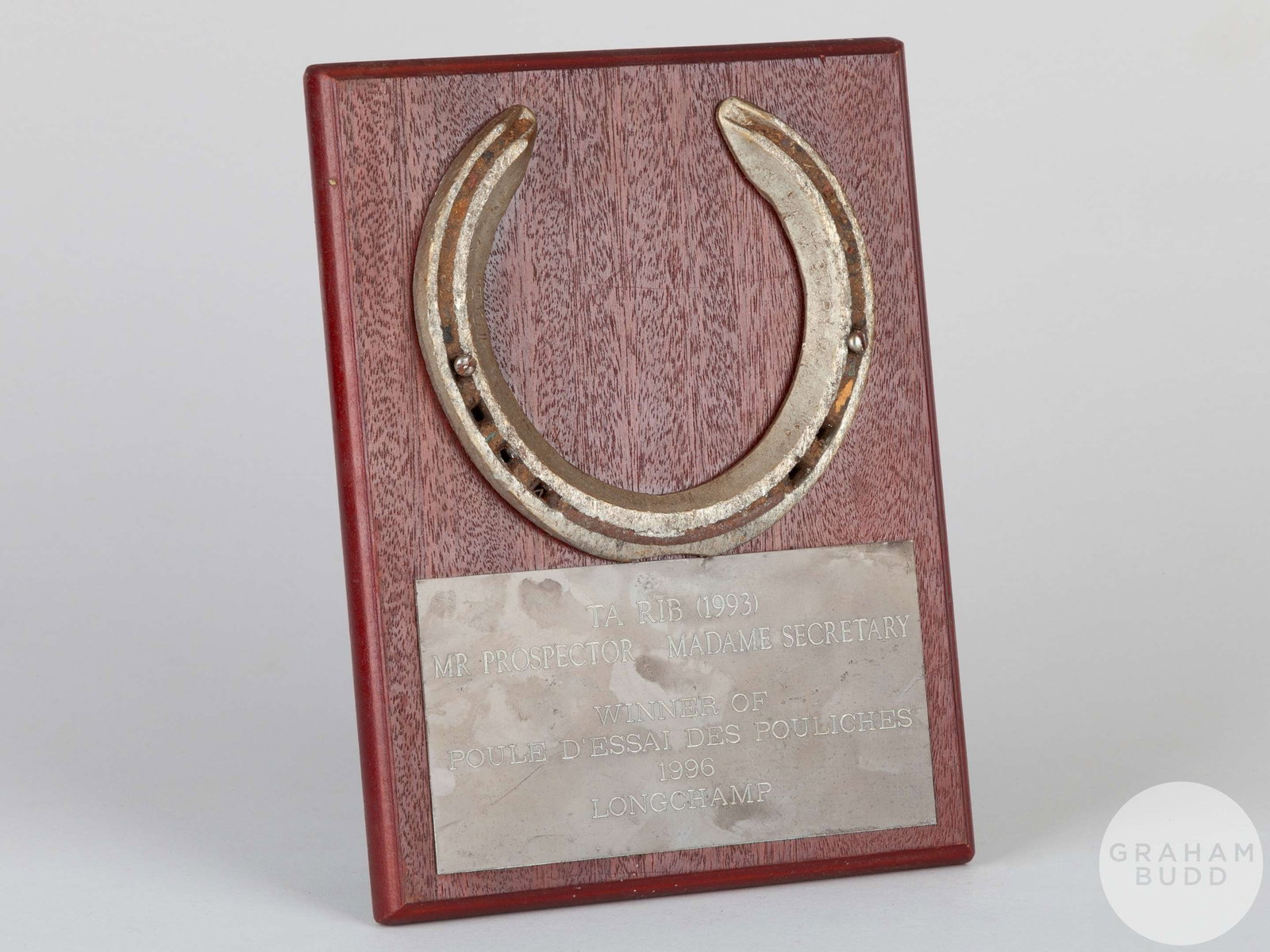 Shoe worn by the racehorse Ta Rib.: Shoe worn by the racehorse Ta Rib, mounted on a wooden plaque with easel support and set with an engraved metal plaque, 20 by 15cm.Provenance: The Ray Goddard Collection Ta Rib was an American-br