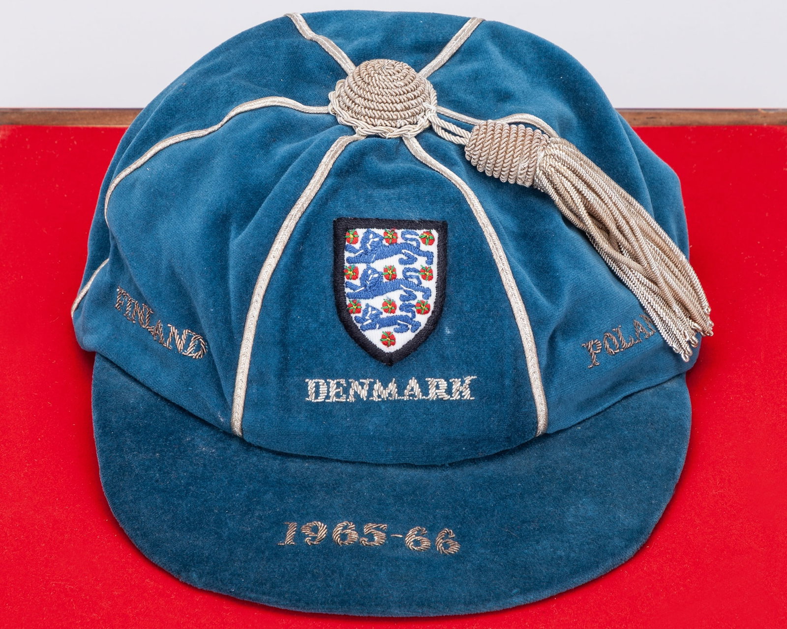Ray Wilson blue England v. Finland, Denmark and Poland international cap, 1965-66: Ray Wilson blue England v. Finland, Denmark and Poland international cap, 1965-66, blue velvet cap with silver tassel and silver braiding inscribed FINLAND DENMARK POLAND 1965-66, in a display case, w
