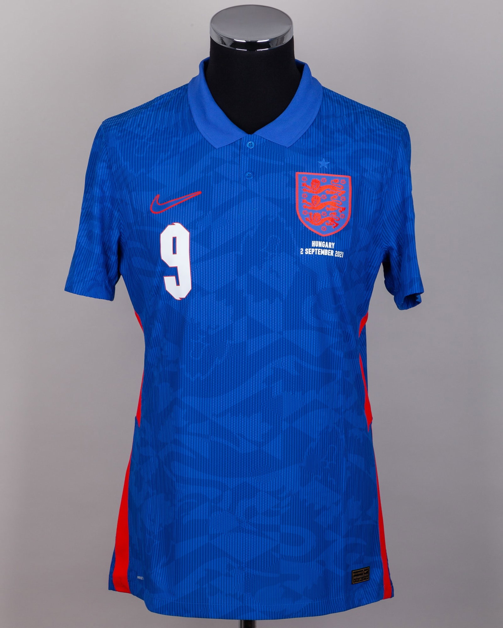 Harry Kane blue No.9 England v. Hungary short-sleeved shirt, 2021: Harry Kane blue No.9 England v. Hungary short-sleeved shirt, 2021, Nike, L, with button-up collar and printed badge, with HUNGARY 2 SEPTEMBER 2021 decal, the reverse lettered KANE, the right sleeve wi