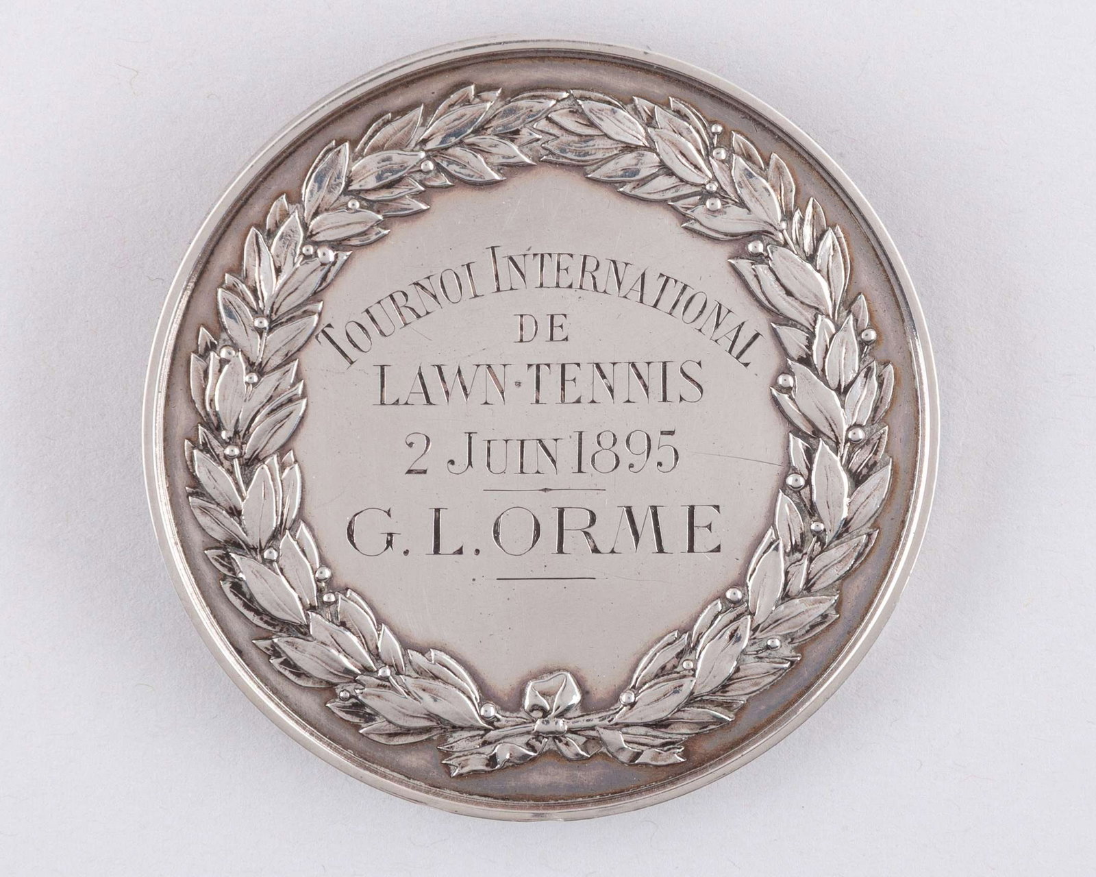 A white-metal Societe de Sport De L'Ile de Puteaux Lawn Tennis medal: A white-metal Societe de Sport De L'Ile de Puteaux Lawn Tennis medal, inscribed Tournoi International de Lawn Tennis, 2 Juin 1895, G.L. Orme The above medal relates to the first ever France v