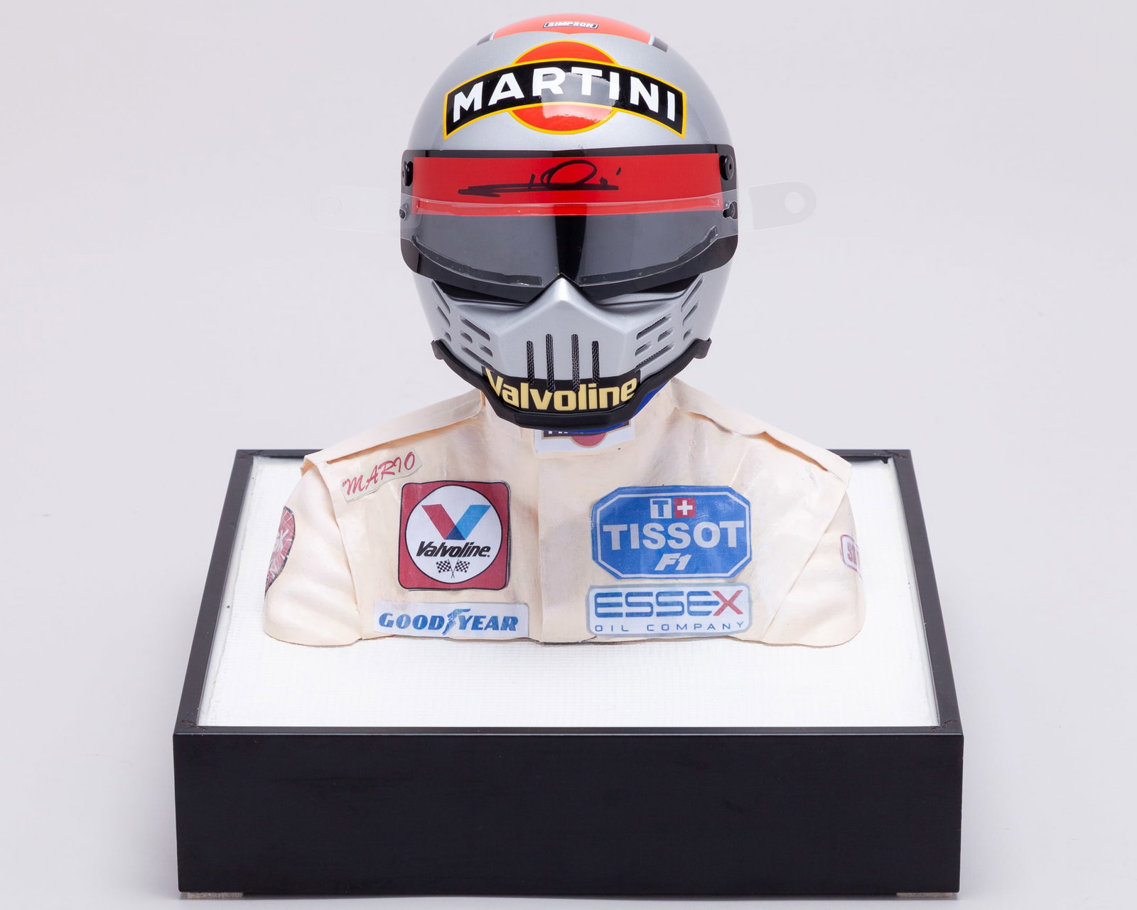Mario Andretti 1979 Signed Lotus 1:2 Scale Helmet Display: Mario Andretti 1979 Signed Lotus 1:2 Scale Helmet Display.Personally signed by the 1978 F1 World Champion. The helmet is the iconic Simpson design.Complete with driver mannequin and display case.