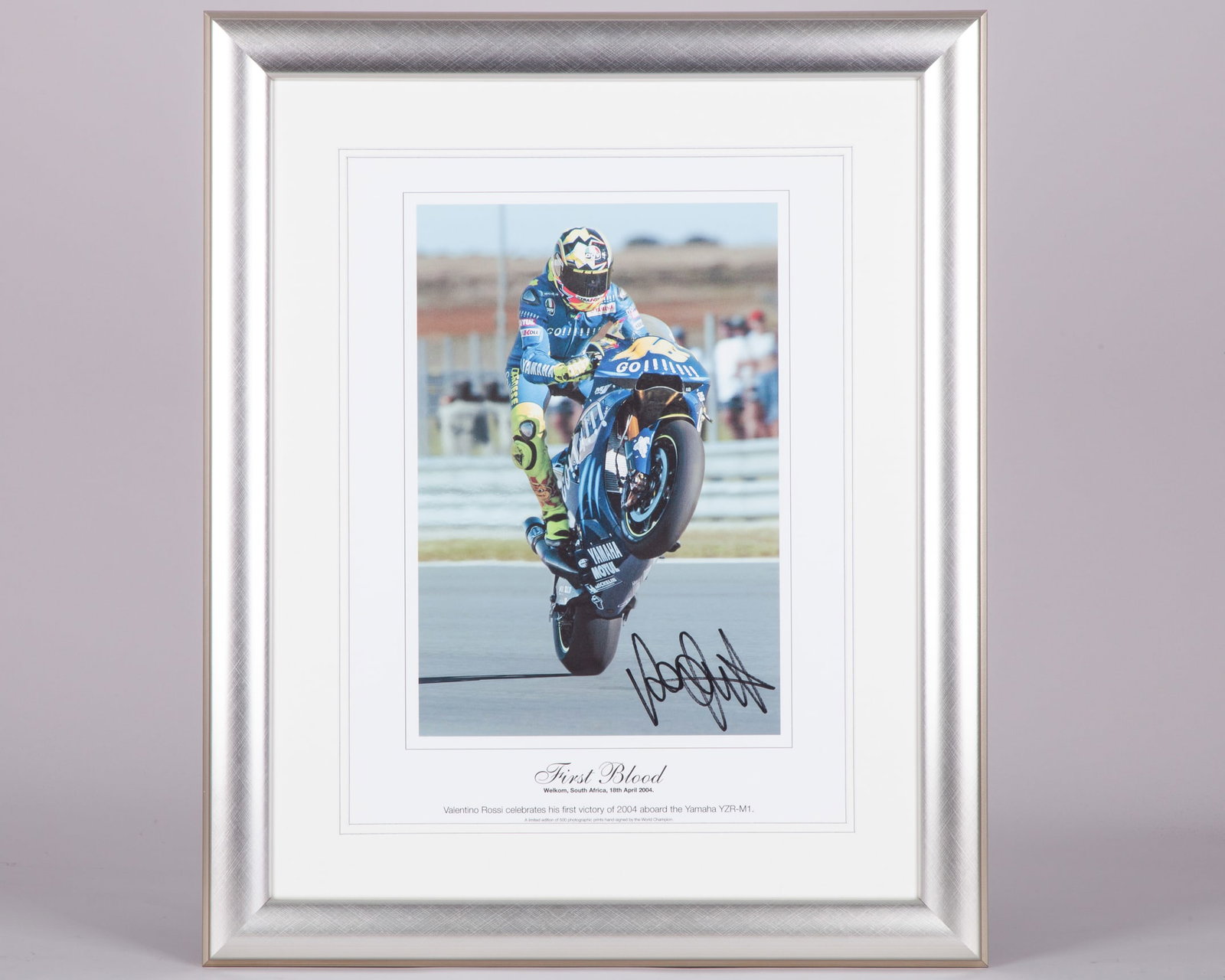 Valentino Rossi 2004 Signed First Victory Limited Edition Framed Print: Valentino Rossi 2004 Signed First Victory Limited Edition Framed Print.This print is personally signed by 7-time MotoGP World Champion Valentino Rossi. Capturing his first victory at the 2004 South Af