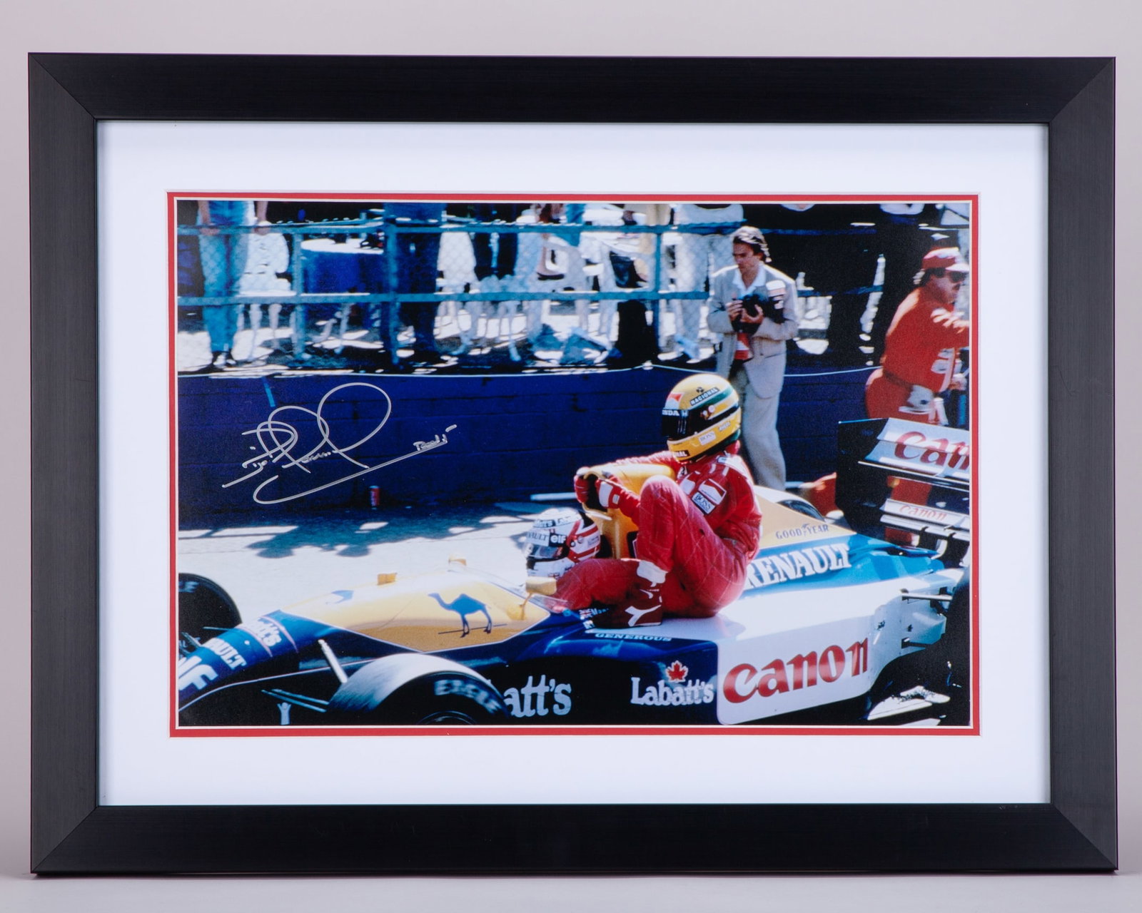 Nigel Mansell Signed “Taxi For Senna” Framed Print: Nigel Mansell Signed “Taxi For Senna” Framed Print. The print captures the iconic moment at the 1991 British Grand Prix where Mansell stopped on the circuit and gave Senna a lift on his Willia
